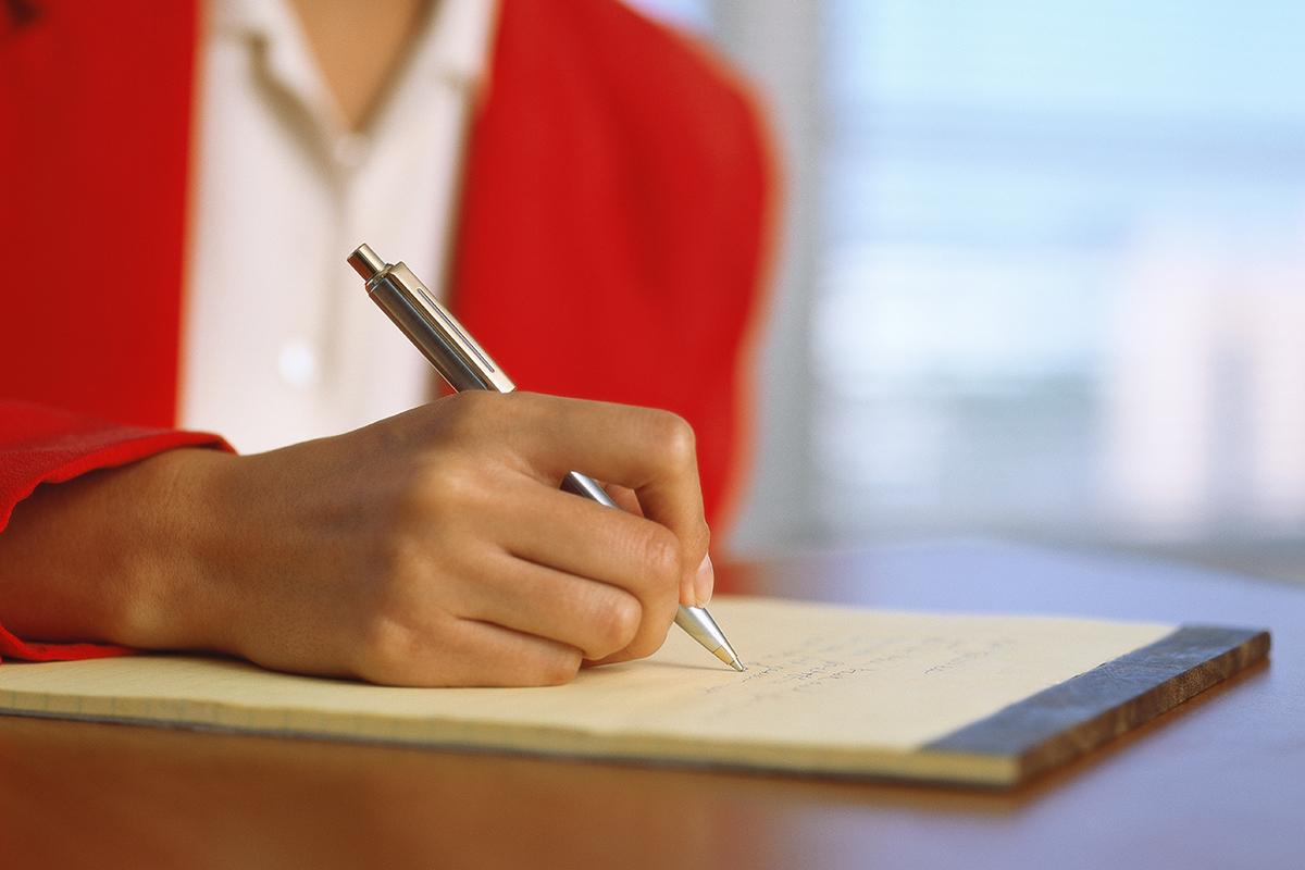 Close-up of a woman writing on a pad
