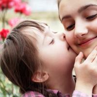 Child with Down Syndrome kissing the cheek of an adult