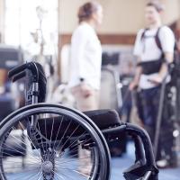 Man receiving physical therapy with wheelchair in foreground.