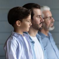 Boy standing in a row with young father behind him and grandfather in back.